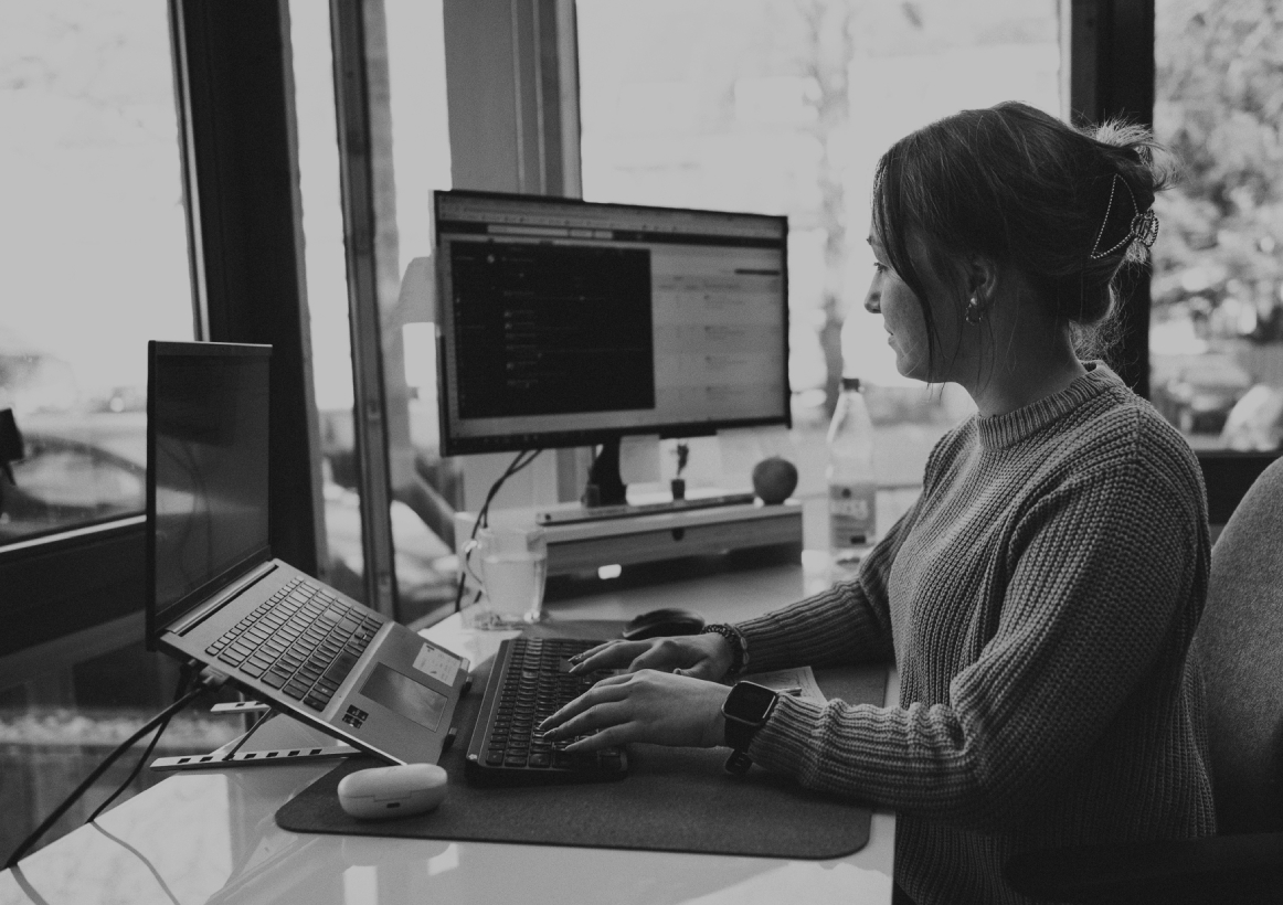Junge Frau sitzt an einem Schreibtisch im modernen Büro und arbeitet konzentriert