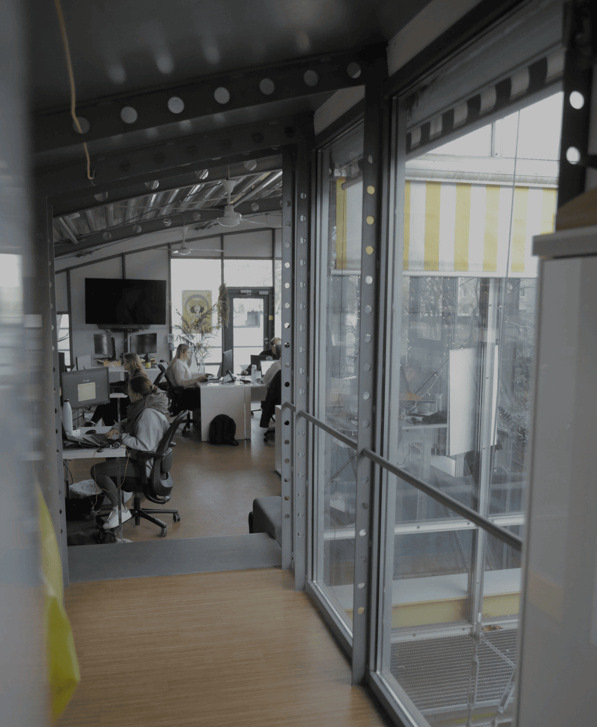 Blick durch eine Glaswand in ein Büro, in dem mehrere Personen arbeiten
