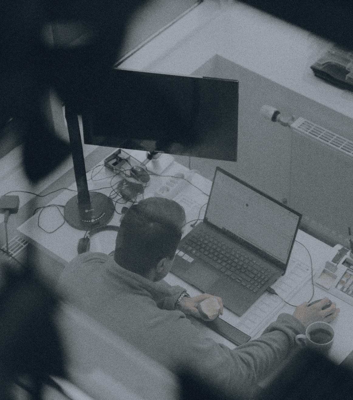 Person arbeitet an einem Laptop am Schreibtisch im Büro, aus erhöhter Perspektive fotografiert