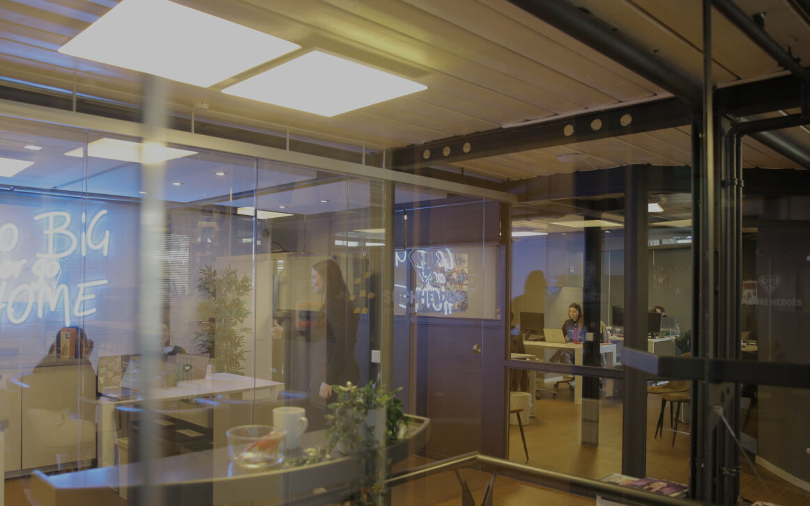 Fotografiert durch Glaswände in ein modernes Büro mit Besprechungsraum und arbeitenden Personen