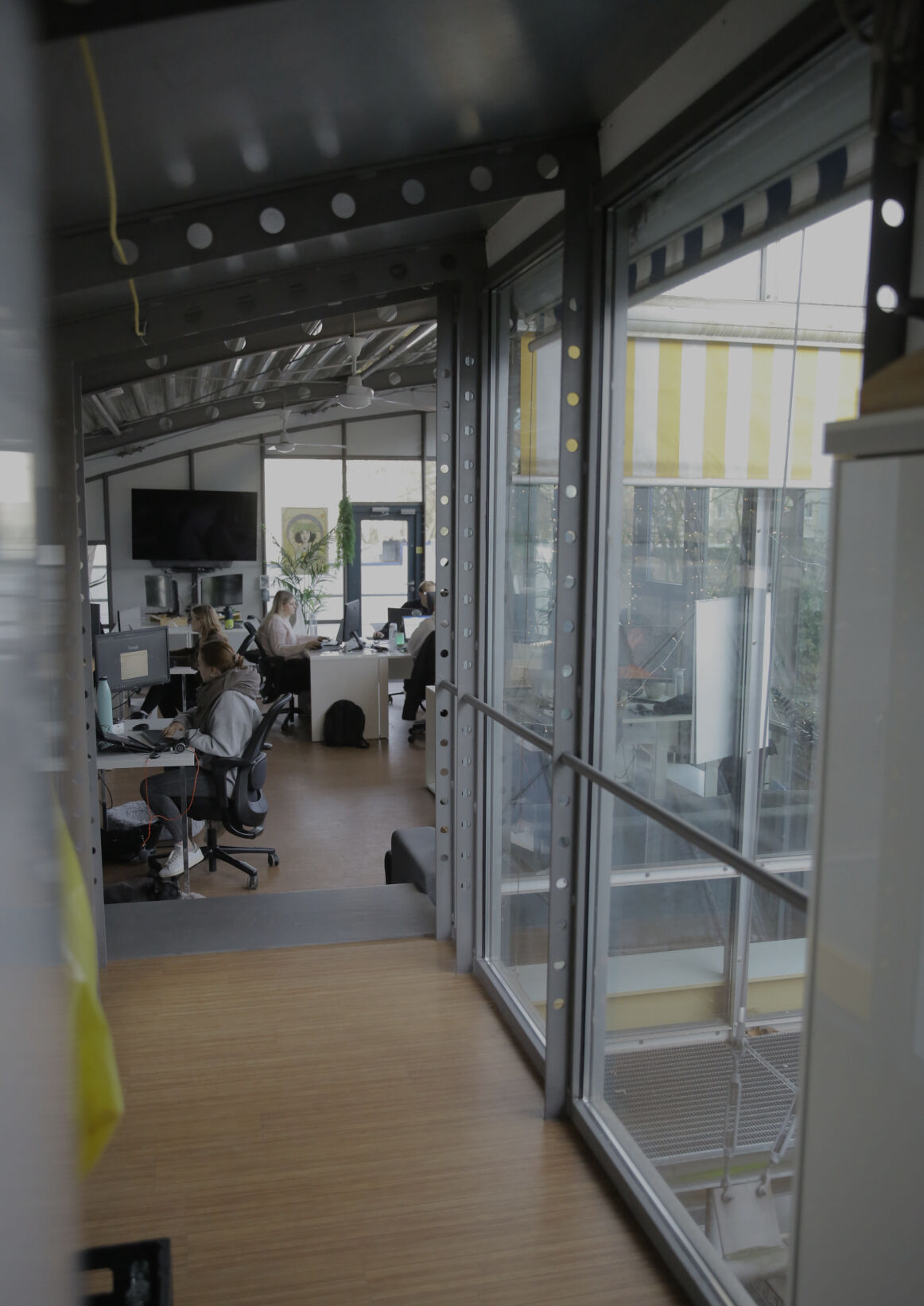 Blick durch eine Glaswand in ein Büro, in dem mehrere Personen an Schreibtischen arbeiten