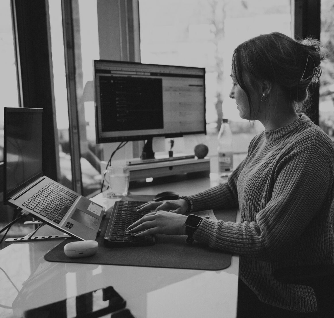 Junge Frau sitzt an einem Schreibtisch im modernen Büro und arbeitet konzentriert